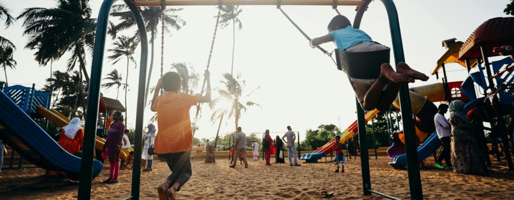 Kids swinging and enjoying a fun day at a tropical playground.