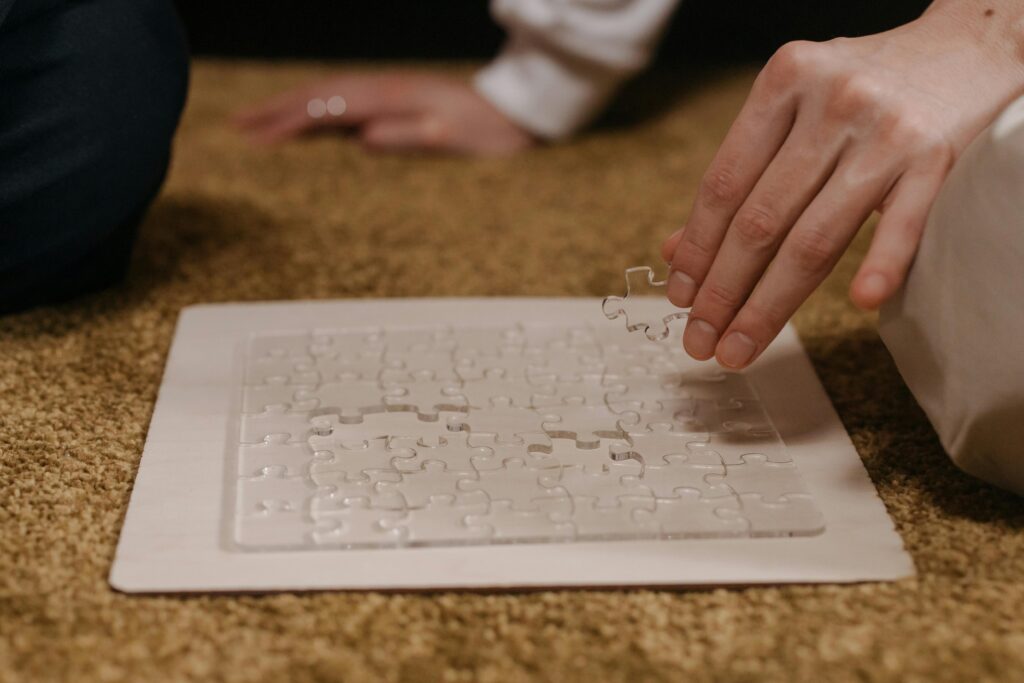 Hand placing piece in transparent puzzle, symbolizing leisure and problem-solving.