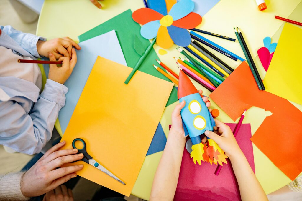 Children engaged in a vibrant arts and crafts session with paper and pencils. Perfect for education and creativity themes.