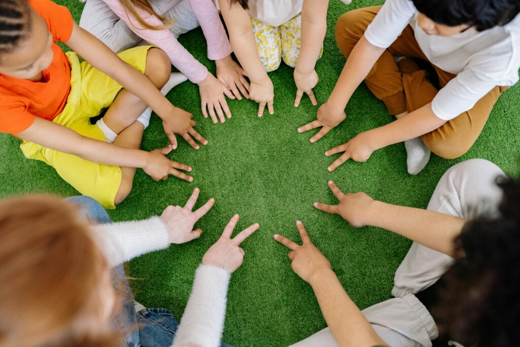 Children sitting in a circle playing fun team games on artificial grass.