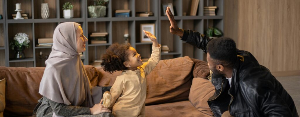 Positive multiethnic family having fun time together near sofa against bookshelves at home
