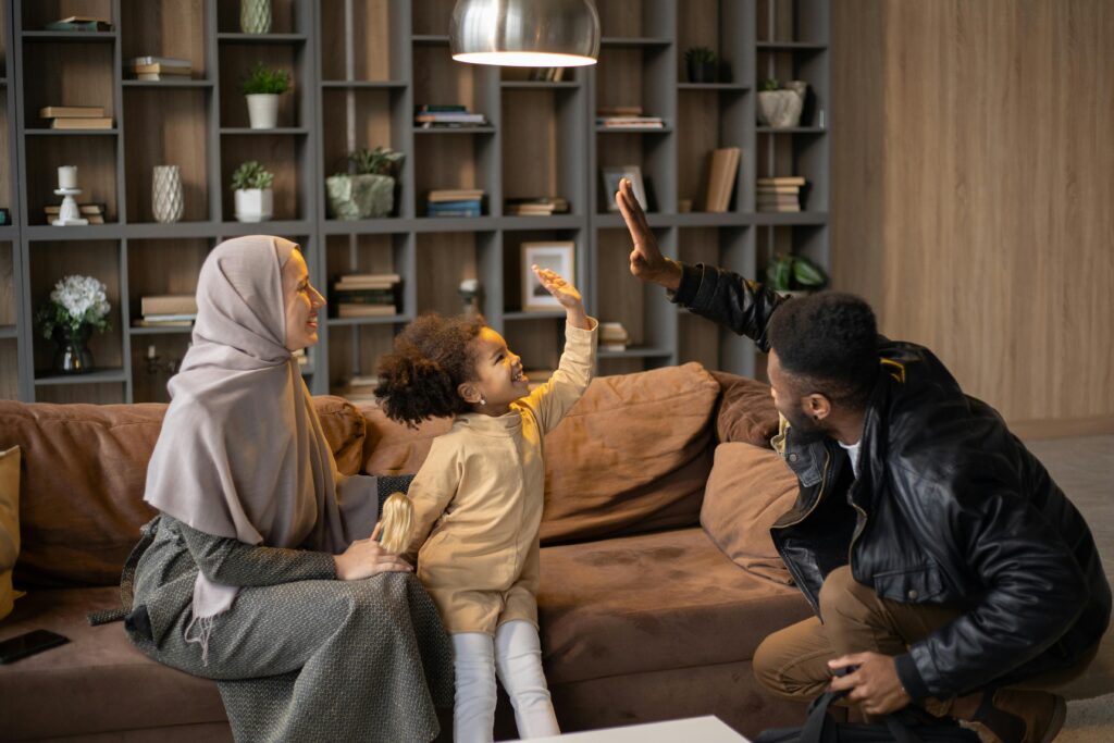 Positive multiethnic family having fun time together near sofa against bookshelves at home